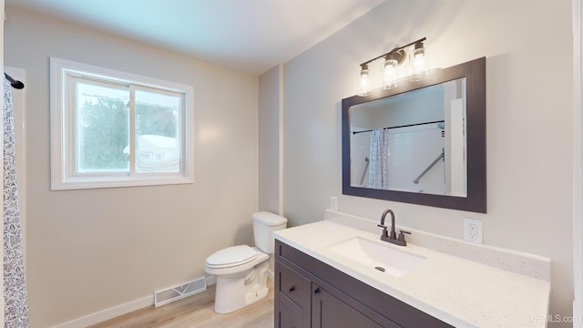 bathroom with hardwood / wood-style flooring, vanity, walk in shower, and toilet