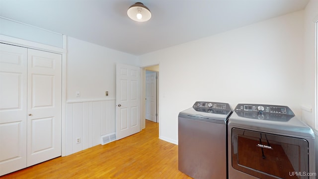 clothes washing area featuring separate washer and dryer and light hardwood / wood-style floors