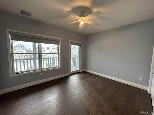 empty room featuring dark wood-type flooring, ceiling fan, and a wealth of natural light