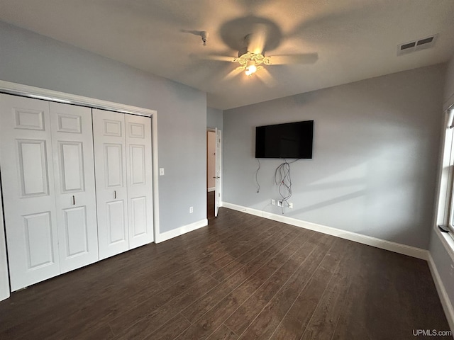 unfurnished bedroom featuring ceiling fan, dark hardwood / wood-style flooring, and a closet