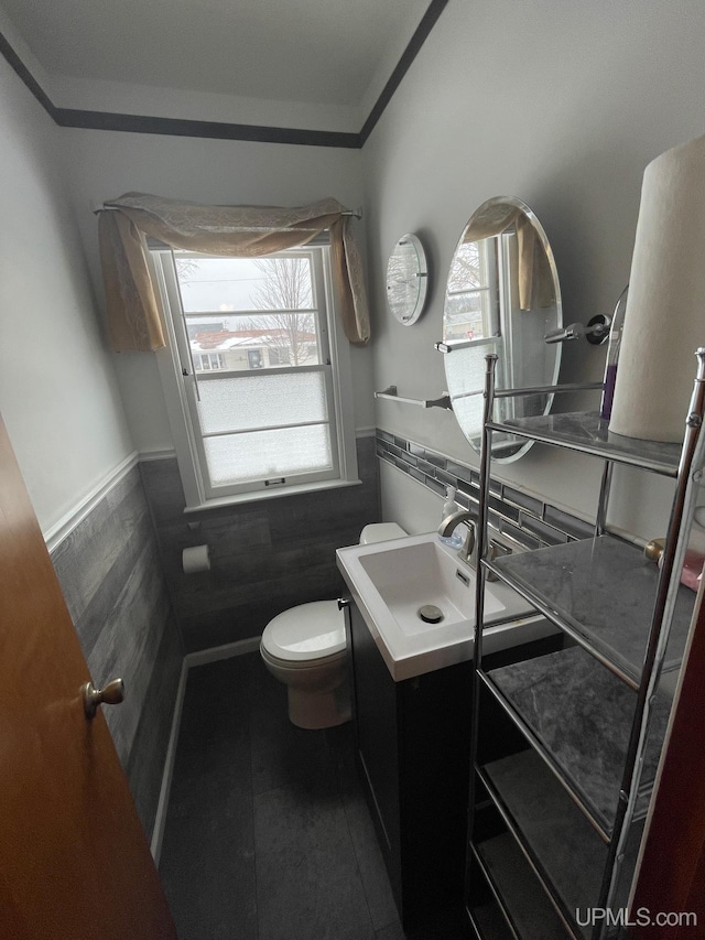 bathroom with vanity, toilet, and tile walls