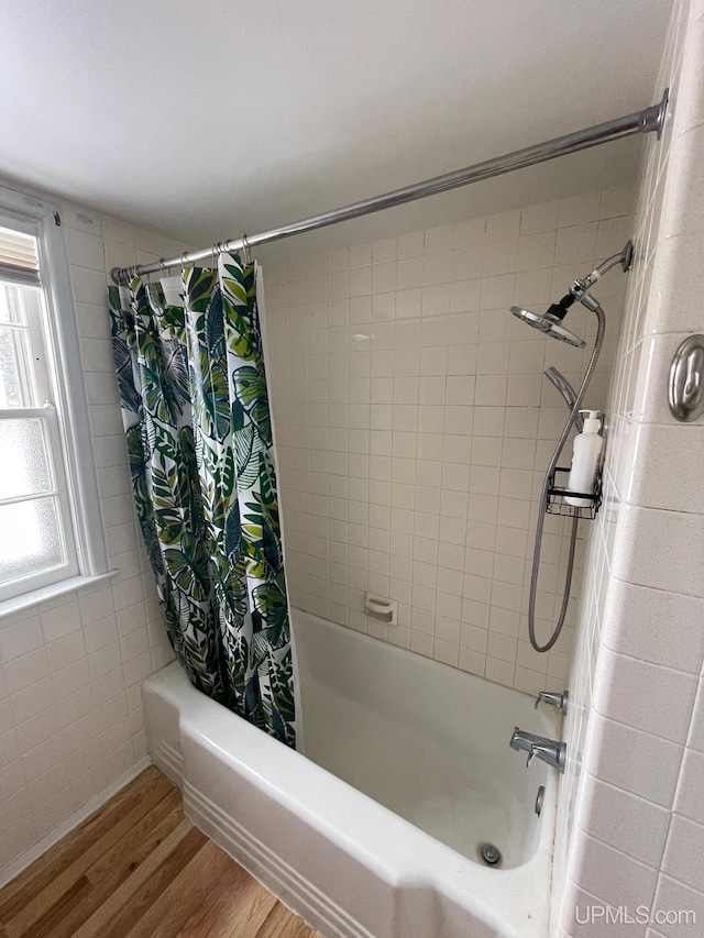 bathroom with shower / tub combo, hardwood / wood-style floors, and tile walls