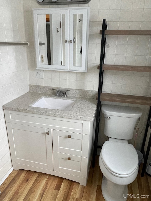 bathroom with vanity, hardwood / wood-style flooring, tile walls, and toilet