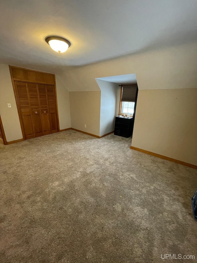 additional living space featuring vaulted ceiling and carpet flooring