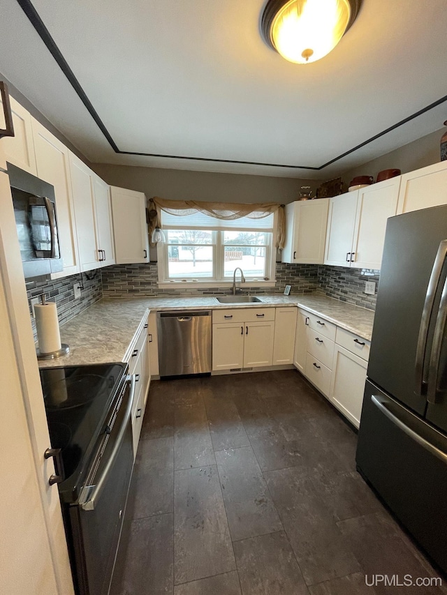 kitchen featuring stainless steel appliances, white cabinetry, sink, and tasteful backsplash