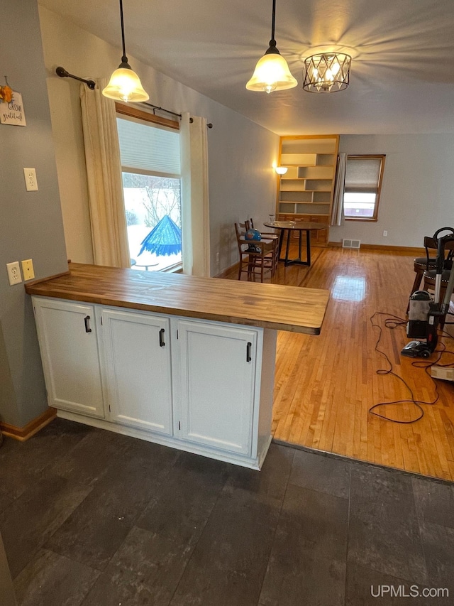 kitchen featuring decorative light fixtures, kitchen peninsula, hardwood / wood-style floors, and white cabinets