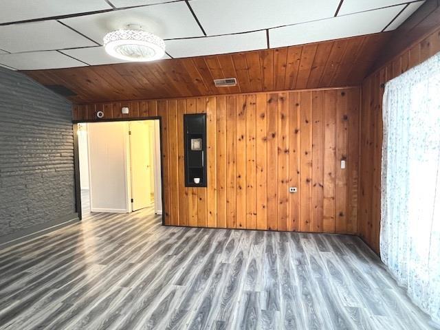 spare room with brick wall, hardwood / wood-style floors, and wooden walls