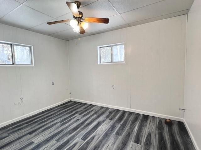 spare room featuring ceiling fan, a healthy amount of sunlight, a paneled ceiling, and dark hardwood / wood-style floors