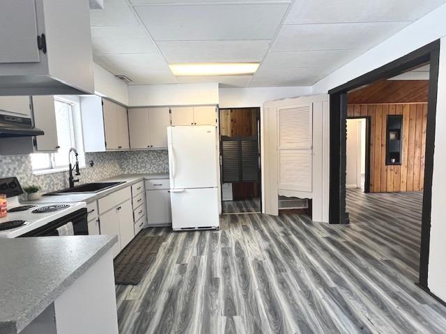 kitchen featuring wood walls, sink, decorative backsplash, white fridge, and electric range