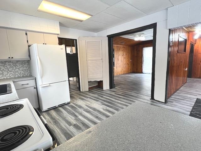 kitchen featuring white appliances, wood walls, and backsplash