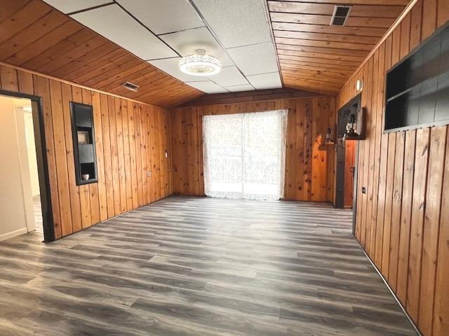 empty room with vaulted ceiling, wooden ceiling, and wood walls