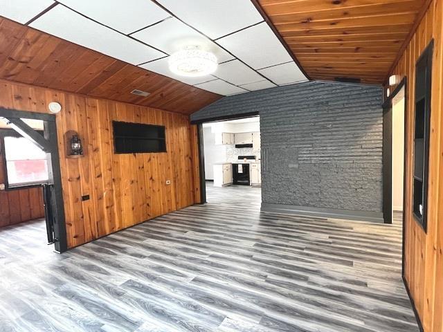 unfurnished living room with wood ceiling, lofted ceiling, hardwood / wood-style floors, and wood walls