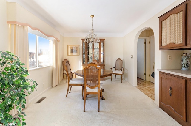 dining area featuring light carpet and an inviting chandelier