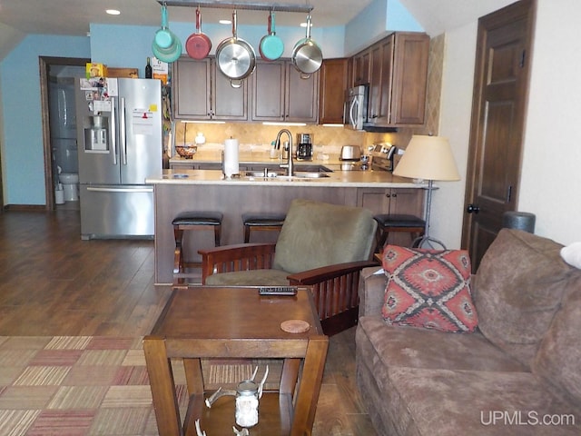 kitchen featuring sink, a kitchen breakfast bar, decorative backsplash, kitchen peninsula, and stainless steel appliances