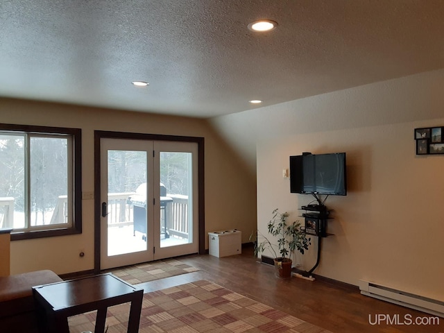 interior space featuring a baseboard radiator, lofted ceiling, hardwood / wood-style floors, and a textured ceiling