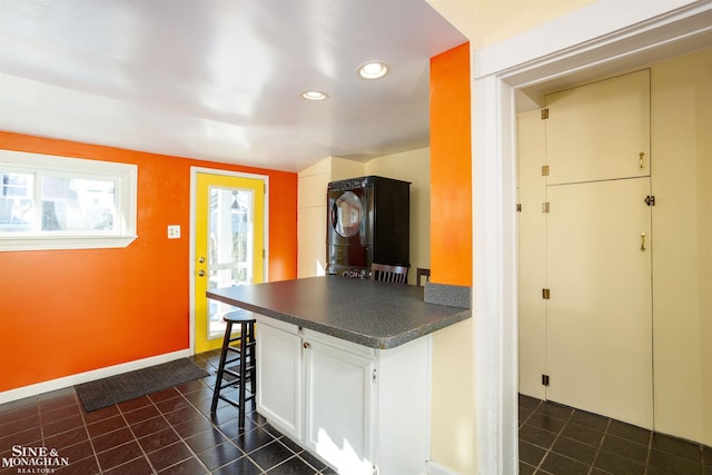 kitchen featuring white cabinetry and stacked washing maching and dryer