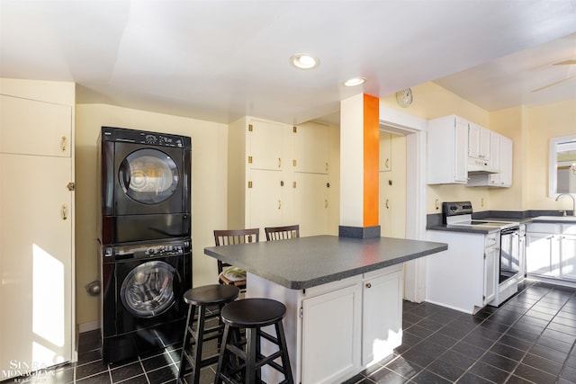 kitchen featuring stacked washing maching and dryer, a breakfast bar, sink, white cabinets, and electric stove