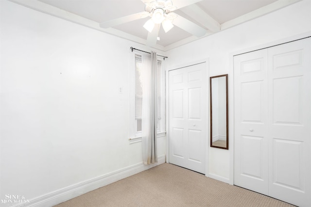 unfurnished bedroom with light carpet, beam ceiling, and ceiling fan