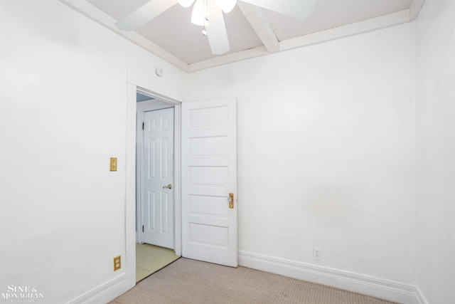 spare room featuring beam ceiling, light carpet, and ceiling fan