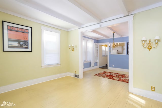 empty room featuring an inviting chandelier, hardwood / wood-style floors, and beam ceiling