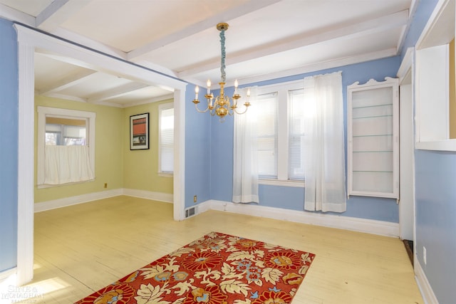 unfurnished dining area with beam ceiling, wood-type flooring, a chandelier, and a healthy amount of sunlight