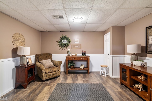 sitting room featuring a drop ceiling and dark hardwood / wood-style floors