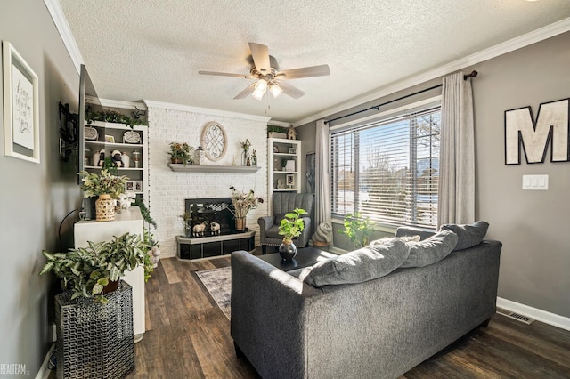 living room with a brick fireplace, crown molding, dark wood-type flooring, and a textured ceiling