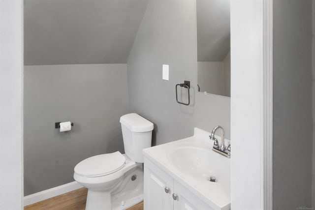 bathroom featuring vanity, hardwood / wood-style floors, vaulted ceiling, and toilet