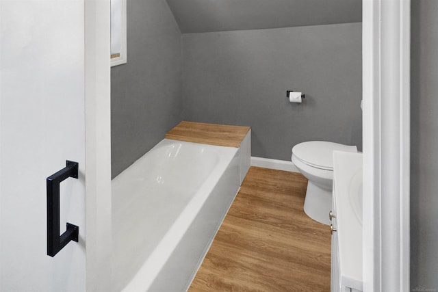 bathroom featuring wood-type flooring, toilet, and a bathtub