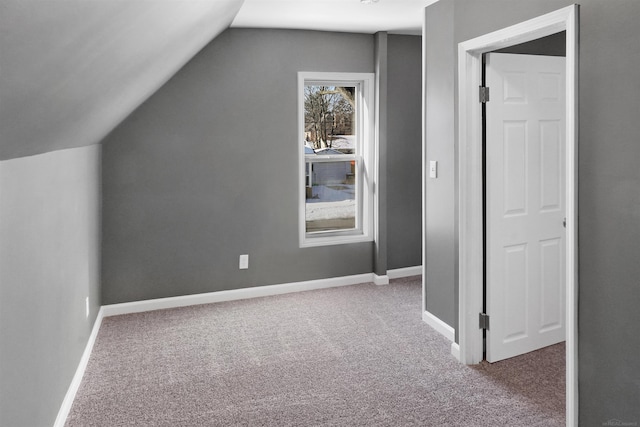 additional living space featuring vaulted ceiling and carpet flooring