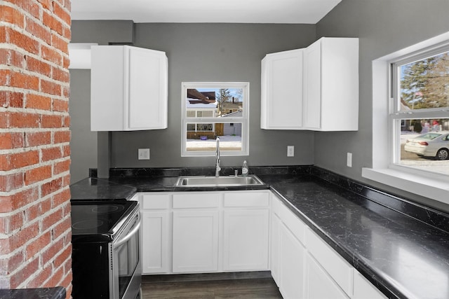 kitchen featuring electric stove, sink, white cabinetry, and plenty of natural light