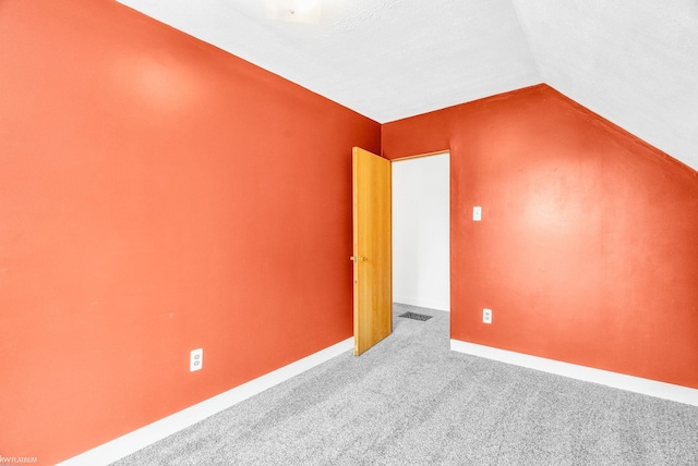 bonus room with vaulted ceiling, carpet floors, and a textured ceiling