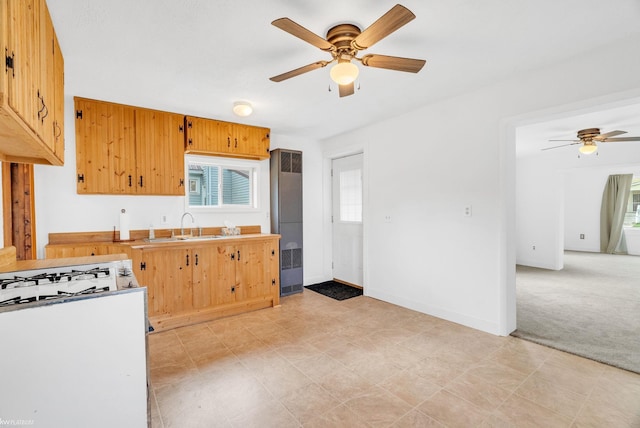 kitchen featuring ceiling fan, sink, and light carpet