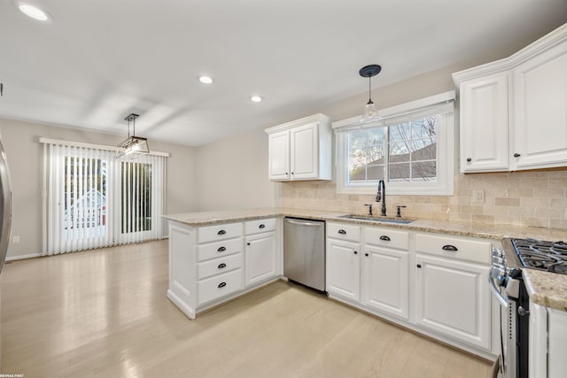 kitchen featuring sink, white cabinetry, hanging light fixtures, appliances with stainless steel finishes, and kitchen peninsula