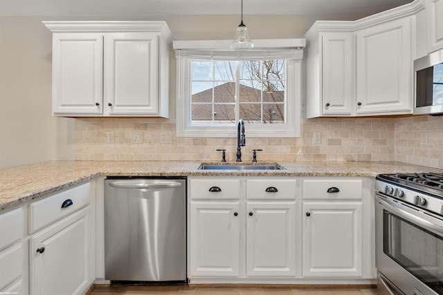 kitchen with hanging light fixtures, white cabinetry, appliances with stainless steel finishes, and sink