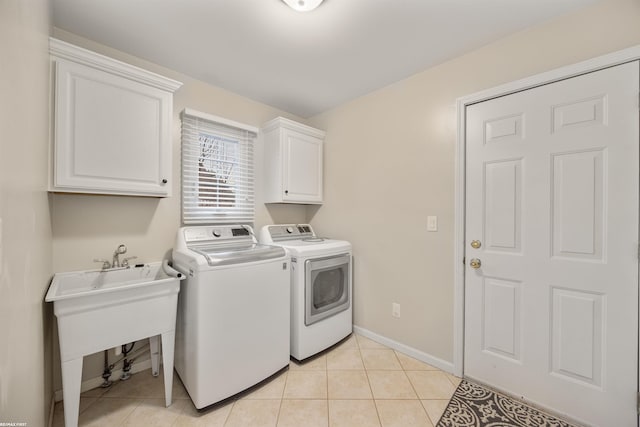 laundry area with cabinets, sink, washer and dryer, and light tile patterned floors