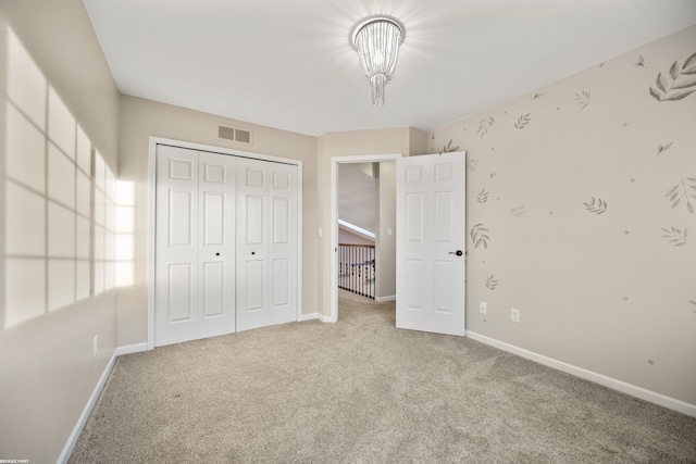 unfurnished bedroom with light carpet, a notable chandelier, and a closet