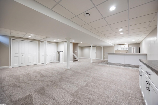 basement featuring stainless steel fridge, a paneled ceiling, and light colored carpet