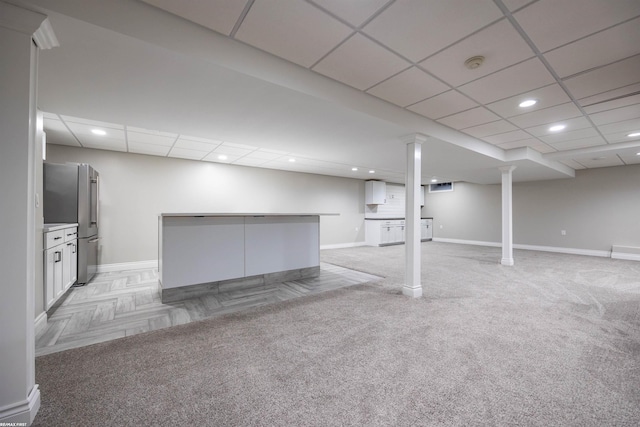 basement featuring light colored carpet, high end refrigerator, and a paneled ceiling