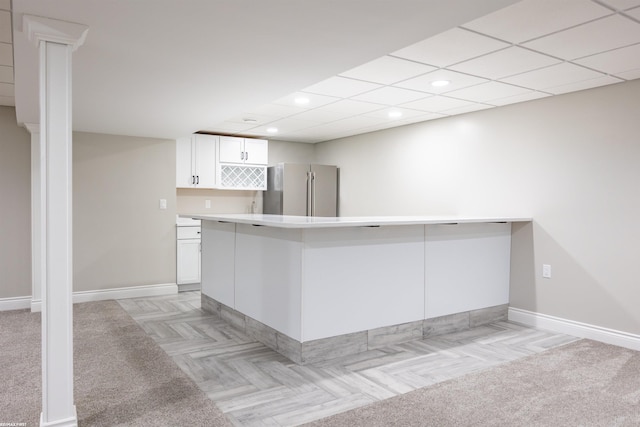 kitchen with white cabinetry, a breakfast bar, kitchen peninsula, and stainless steel refrigerator