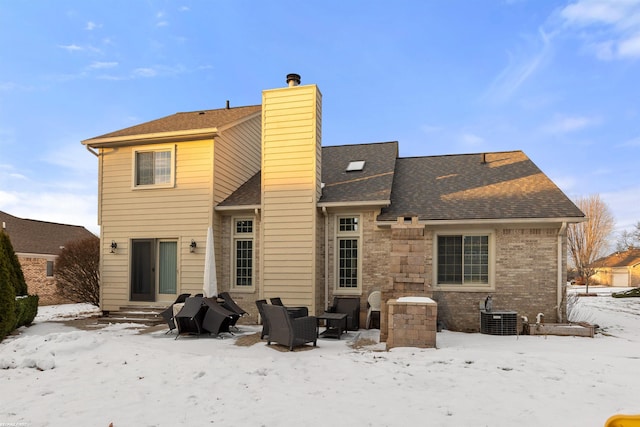 snow covered rear of property with cooling unit