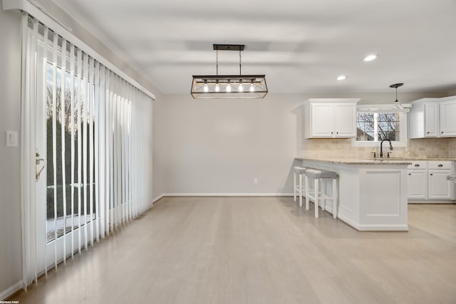 kitchen featuring hanging light fixtures, white cabinetry, and a kitchen bar