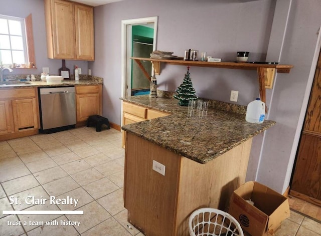 kitchen featuring dark stone countertops, sink, light tile patterned floors, and stainless steel dishwasher