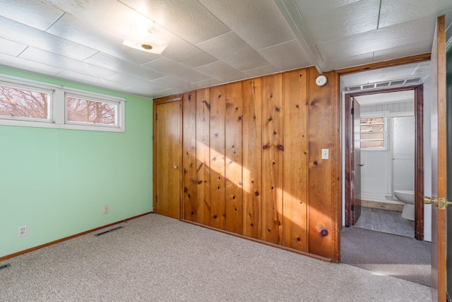 empty room featuring carpet floors and wooden walls