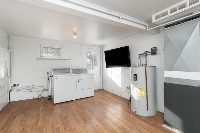 laundry area with washing machine and dryer, water heater, and light hardwood / wood-style flooring