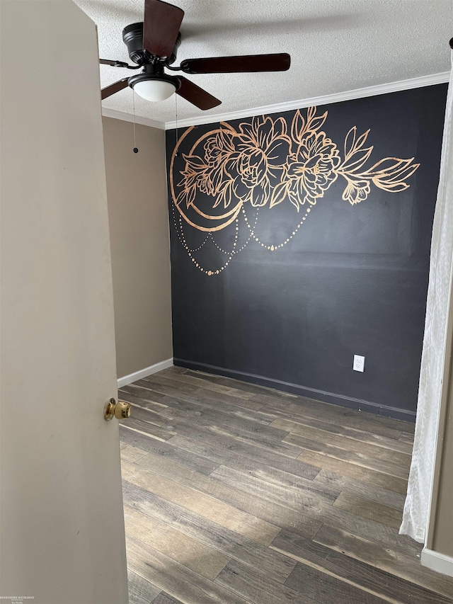 empty room featuring ornamental molding, a ceiling fan, a textured ceiling, wood finished floors, and baseboards