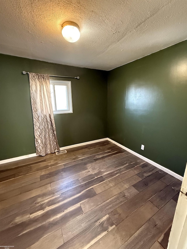 unfurnished room with baseboards, wood-type flooring, and a textured ceiling