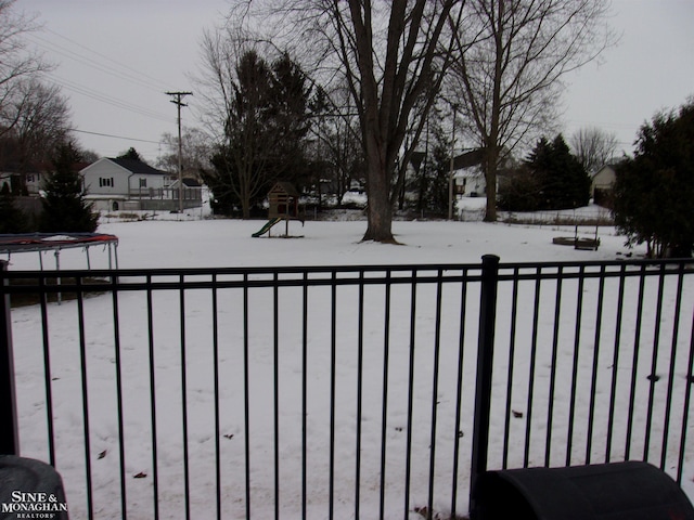 yard layered in snow with a trampoline