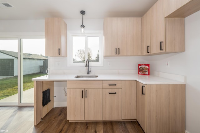 kitchen featuring hanging light fixtures, sink, light brown cabinets, and dark wood-type flooring