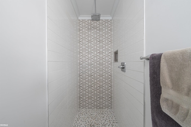 bathroom featuring ornamental molding and a tile shower